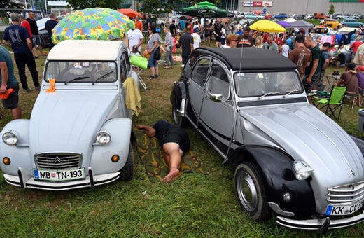 A man sleeps between two parked cars the 23rd 2cv World Meeting 2019 in Samobroe, near Zagreb, on August 2, 2019.