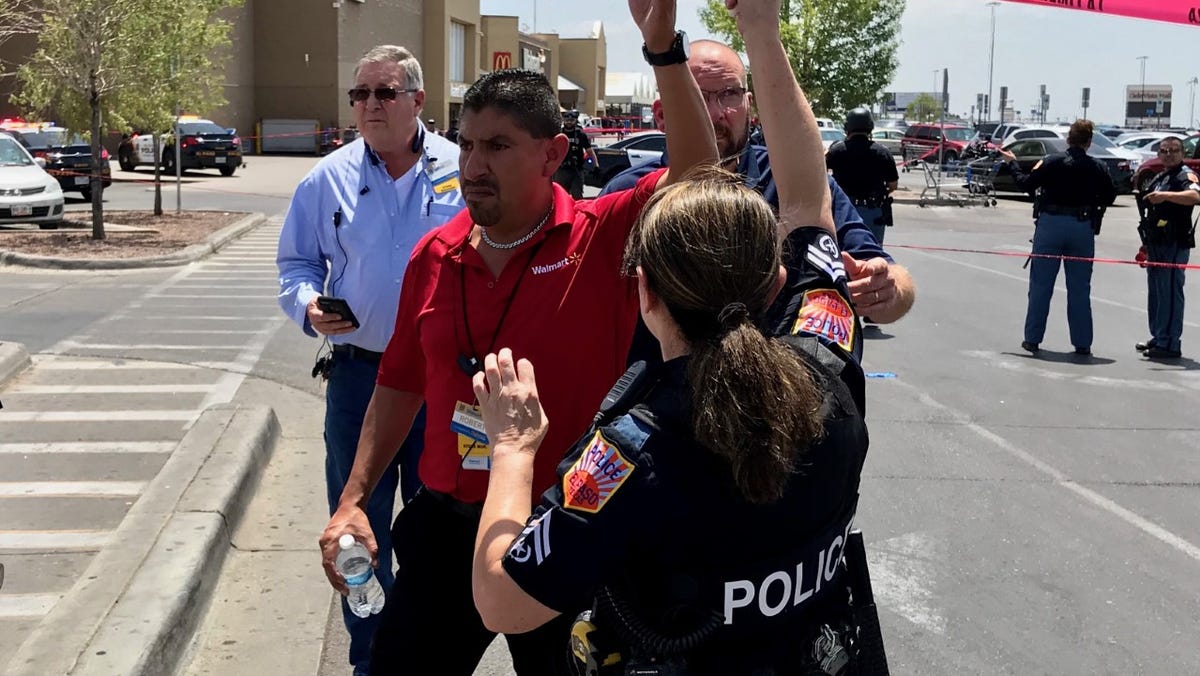 An El Paso police officer lifts the tape barrier at the shooting scene at the Walmart in the Cielo Vista area on Saturday, Aug. 3, 2019.