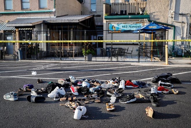 Shoes are piled outside the scene of a mass shooting including Ned Peppers bar, Sunday, Aug. 4, 2019, in Dayton, Ohio. Several people in Ohio have been killed in the second mass shooting in the U.S. in less than 24 hours, and the suspected shooter is also deceased, police said. (AP Photo/John Minchillo)