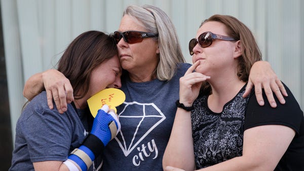 Joan Fultz, center, embraces her daughter's Emily...