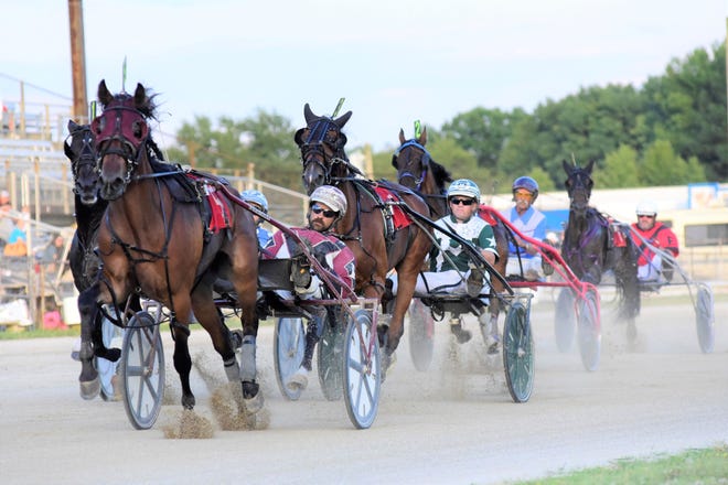A group of drivers speed into the second lap of their harness race Monday evening during the Richland County Fair.