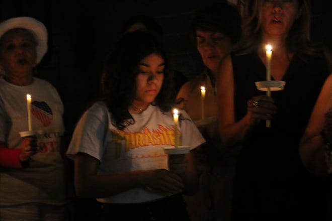 Community members listen to a prayer at a candlelight vigil in Phoenix for victims of the Dayton, Ohio and El Paso, Texas shootings.