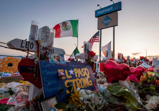 People  pay their respects at the makeshift memorial for victims of the shooting that left a total of 22 people dead at the Cielo Vista Mall WalMart (background) in El Paso, Texas.