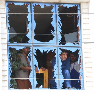 People peer through damaged window panes near the scene of a bomb blast in Herat, Afghanistan on August 7, 2019.