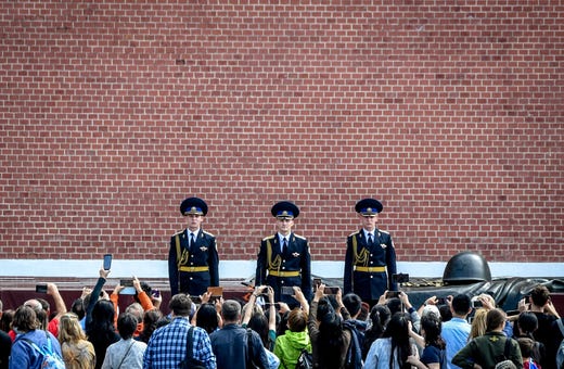 People take pictures of Russian honour guards during the changing of the guards ceremony at the Tomb of the Unknown Soldier by the Kremlin wall in Moscow on August 7, 2019.