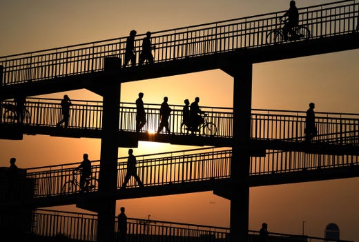 Asian labourers cross a pedestrian bridge in Dubai on August 7, 2019, as they head to work at a vegetable market.