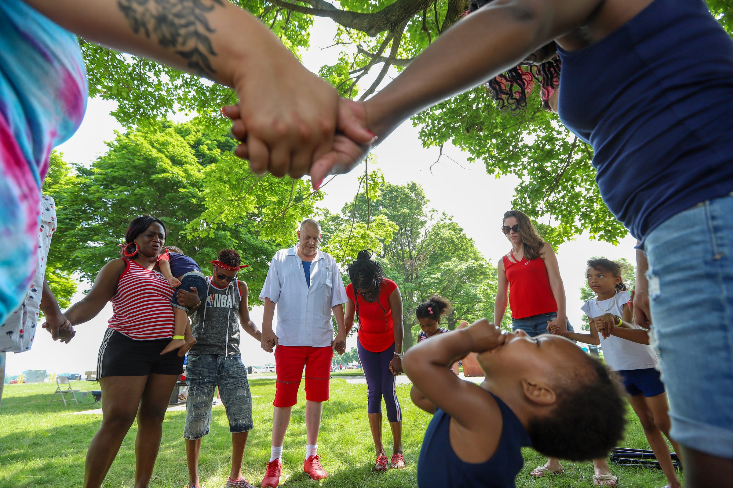 Family members gather to pray before they eat lunch during the Cushingberry family reunion at Belle Isle in Detroit on July 6, 2019. Over 200 hundred members are expected as each immediate family spreads out over a section of the park.