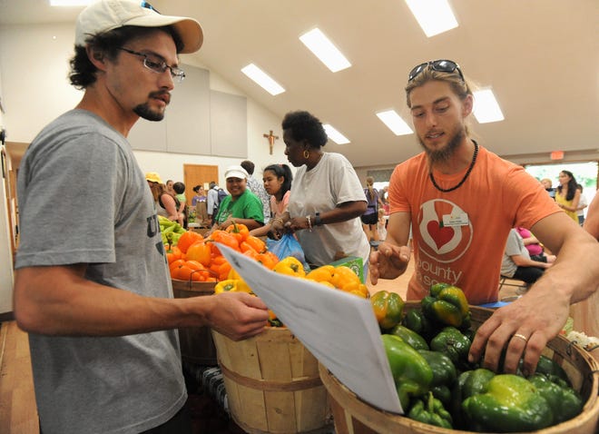 Adam Kelly, right, the food sourcing and volunteer coordinator for Bounty & Soul,  works with a volunteer during the Aug. 6 market at St. James Episcopal Church.