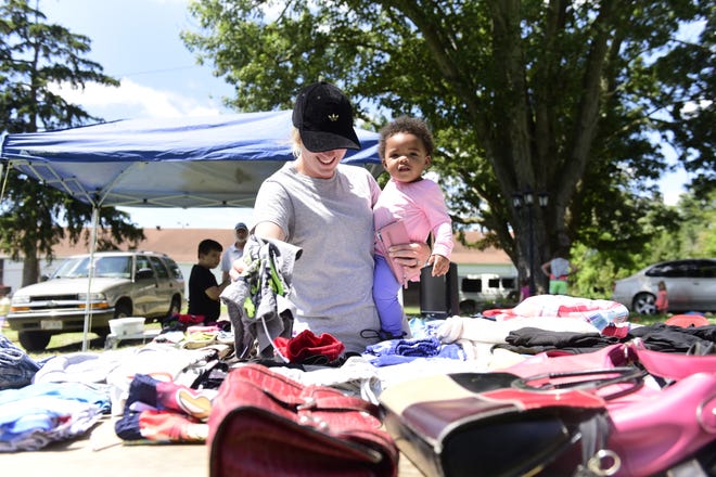 Lenzie Gray and her one-year-old daughter, Niayeli, both of Bucyrus, look through items at a Crestline yard sale during the annual Lincoln Highway Buy-Way sale.