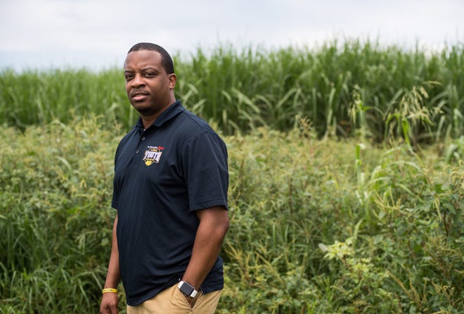 Belle Glade native Pastor Steve Messam says the smoke from burning sugar cane fields, like the one pictured behind him near Glades Central Community High School on July 25, 2019, affects his family's health, including 5-year-old son Noah.