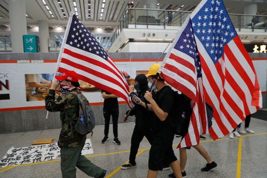 Protesters carry U.S. flags during a demonstration at the airport in Hong Kong on Aug. 9, 2019. Pro-democracy activists rallied at the airport Friday even as the city sought to reassure visitors of their welcome despite the increasing levels of violence surrounding the 2-month-old protest movement.