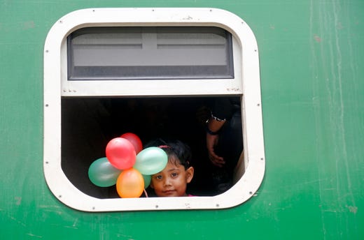 A child holding balloons looks out from the window of a train as people travel to their home villages to celebrate Eid-al-Adha, at the Kamlapur Railway Station in Dhaka, Bangladesh on August 9, 2019.