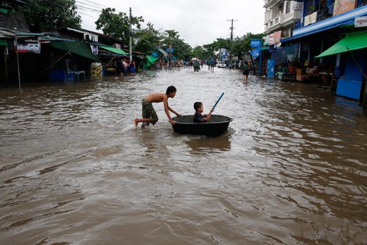 Myanmar boys play at flooded road in Mawlamyine, Mon State, Myanmar on Aug. 10, 2019. Reports state more than 100,000 people have been displaced by floods in several areas across Myanmar due to heavy monsoon rain. 