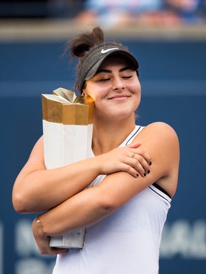 Bianca Andreescu hugs the winner's trophy after defeating Serena Williams.