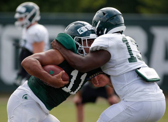 Michigan State running back Connor Heyward, left, and linebacker Marcel Lewis run a drill during an NCAA college football practice, Monday, Aug. 12, 2019, in East Lansing, Mich.
