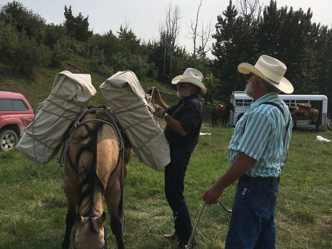 Greg Schatz tightens a manty rope while Bob Hermance keeps his horse relaxed. Fourteen teenagers from Montana, Alberta and Mexico learned to pack horses at Boone and Crockett's summer camp.