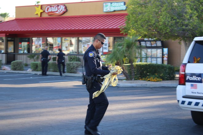 A police officer balls up police tape after the Carl's Jr. was determined safe for people to reenter. Police were responding to reports that a man with a gun was inside the restaurant.