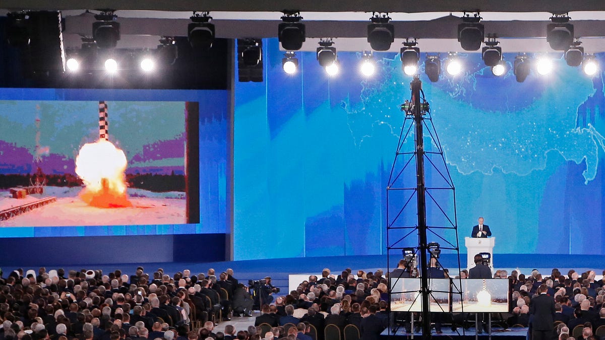 Russian President Vladimir Putin delivers his annual address to the Federal Assembly while a screen shows a newly developed cruise missile with 'no range limitation' at the Manezh Central Exhibition Hall in Moscow.
