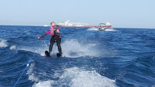 Madelyn Hendrickse skis past an ore freighter on Lake Michigan.