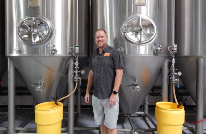 Jeff Huss stands in front of two of the four tanks that started it all six years ago at Huss Brewing.