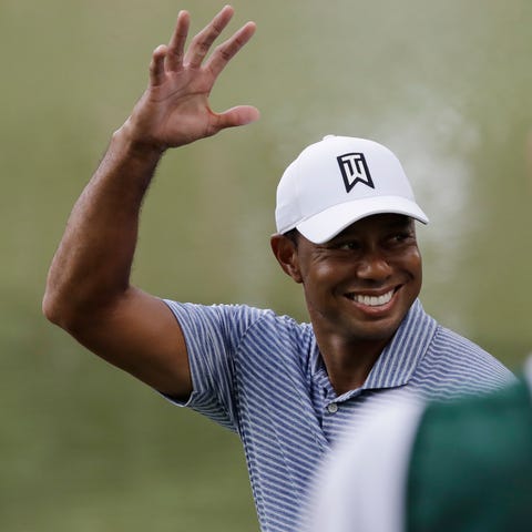 Tiger Woods smiles as he greets fans on the 14th...