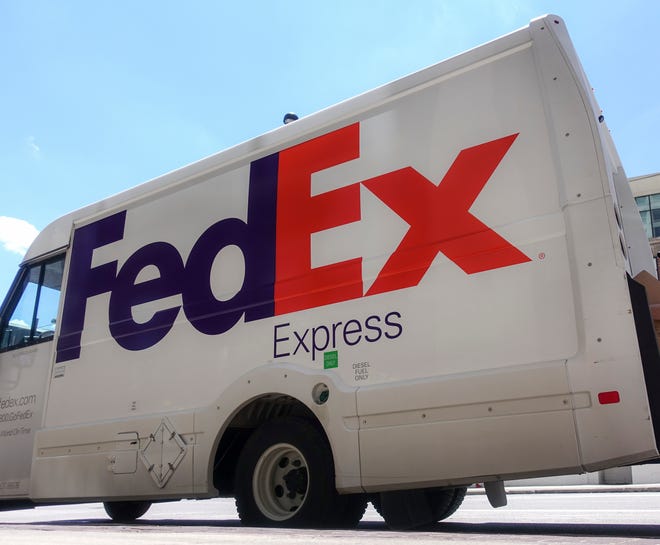 A FedEx delivery truck is loaded by an employee.