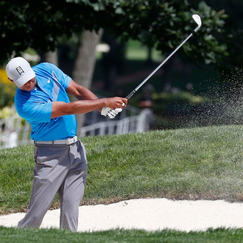 Tiger Woods hits out of a fairway bunker on the...