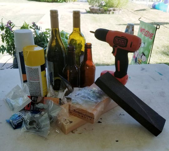 Material needed to make a recycled bottle wall vase include: old wine, beer or soda bottles; cleaned of labels; washed inside and out and dried 2x4 stud; cut into 8" OR 12" length; sand paper; paint primer; paint or wood stain in your choice of color; and saw tooth picture hangers.