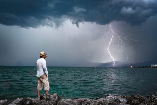 A man stands on rocks as lightning strikes over Lake Geneva on Aug. 6, 2019 near Le Bouveret, Switzerland.