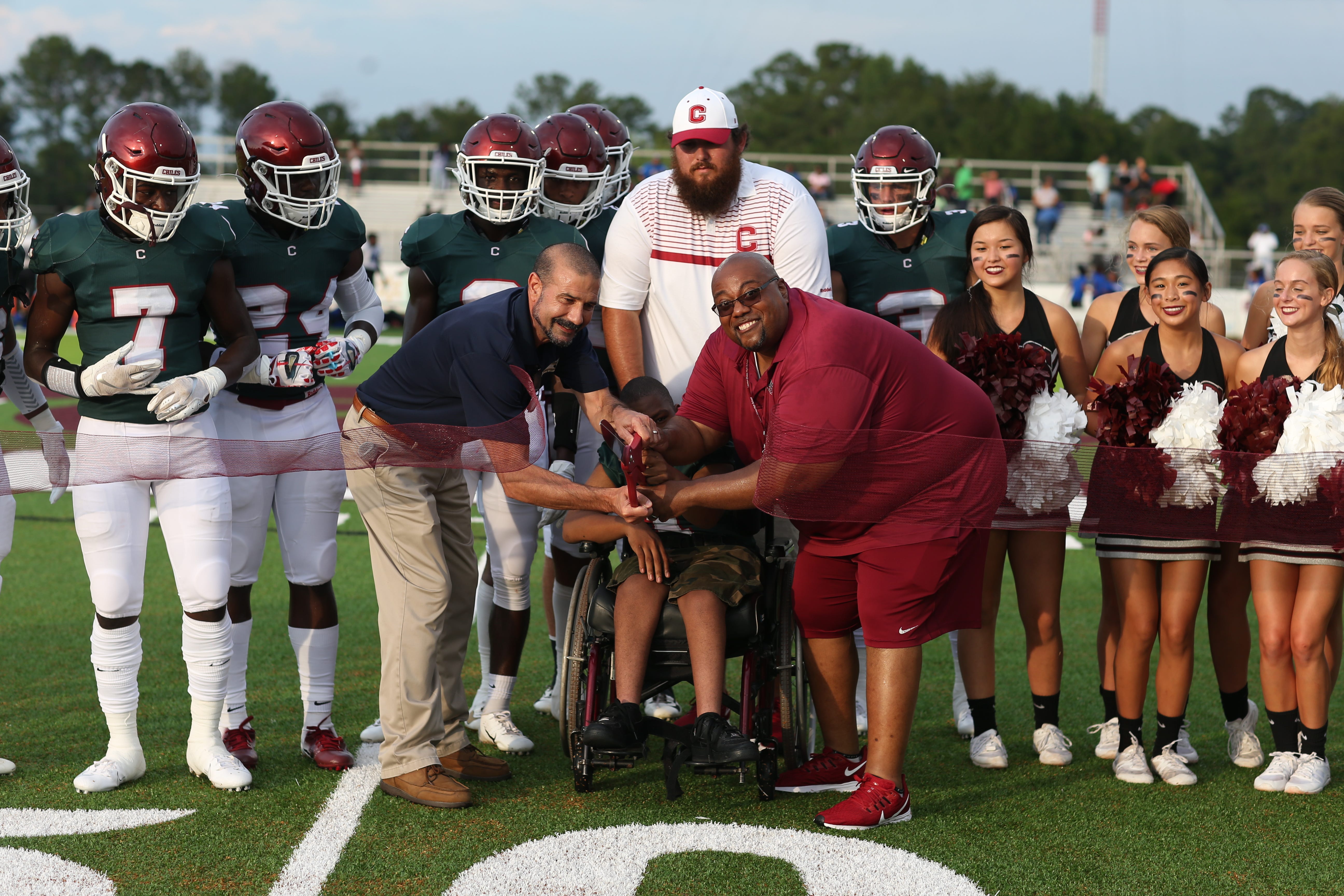 Leon County Schools Superintendent Rocky Hanna cuts a ribbon with the help with Chiles High School student Shareef Gaymon, center, marking the first game on the new turf at Chiles High School Friday, August 16, 2019. 