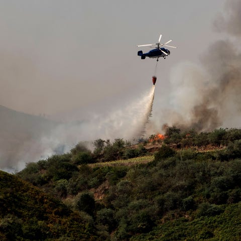 A helicopter operates over a wildfire in Canary...