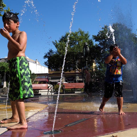 Children play in jets of water at the Lizzie...
