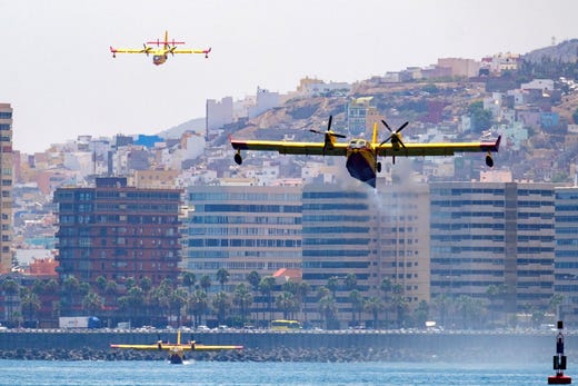 Two firefighter planes land on water to load more water during the fight against wildfires in forests in Gran Canarias Canary Islands, Spain on Aug. 19, 2019. About 8,000 people have been evacuated from their houses as fire continues to burn land in the area since Aug. 17, 2019. Approximately 14,800 acres have burned in the third fire in a week registered in the island.