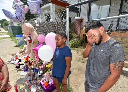 Francisco Hernandez, uncle of nine-year-old dog-mauling victim Emma Hernandez grieves the tragic loss of his niece as he stands with Tira Nowden, 9, of Detroit beside a makeshift memorial in front of Emma's house.