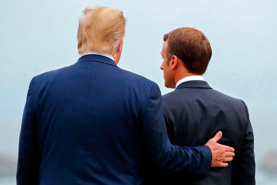 President Donald Trump puts his hand on the back of French President Emmanuel Macron as they pose ahead of a working dinner at the G-7 summit in Biarritz, France.
