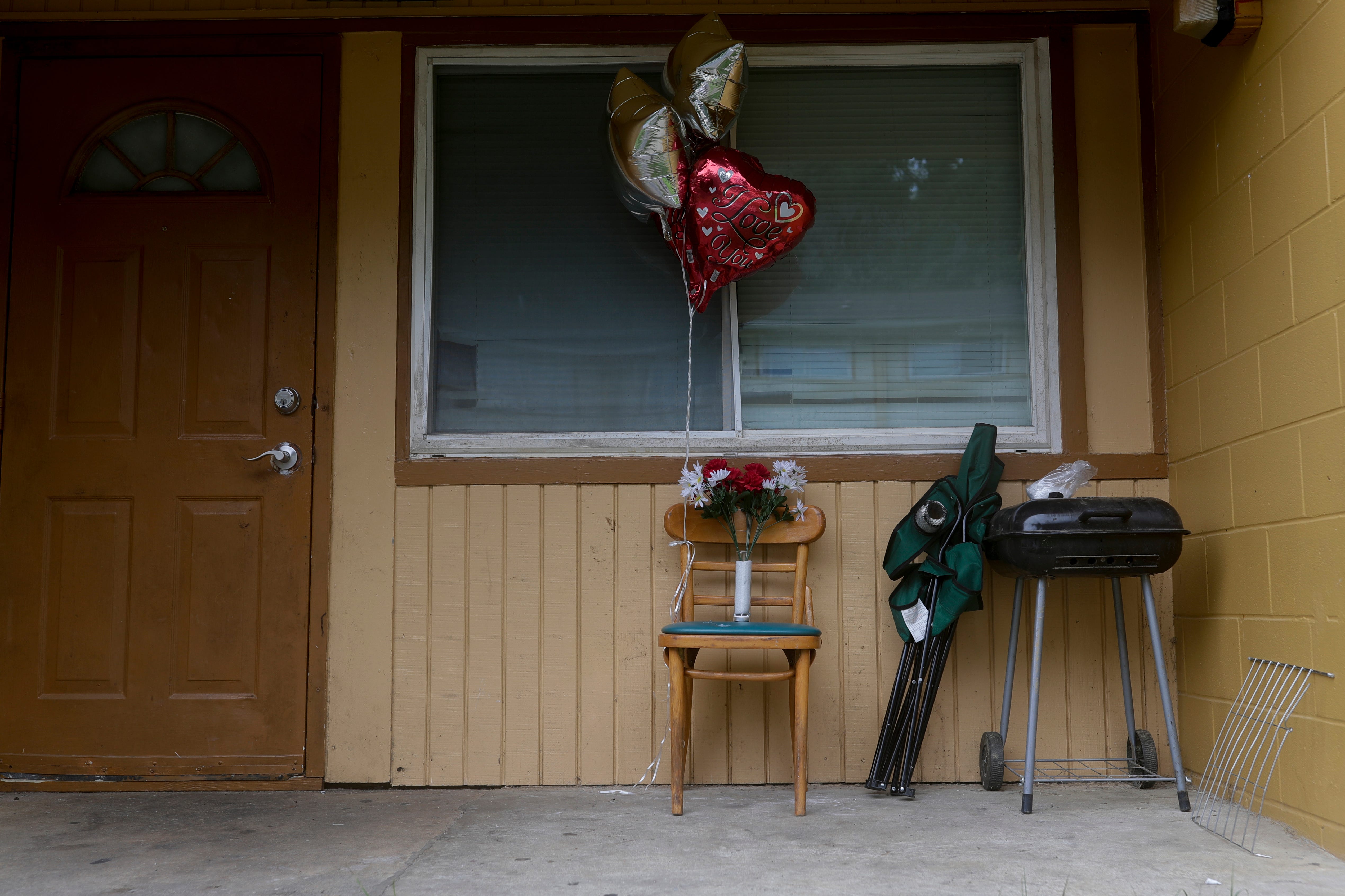 Balloons, a single candle and a bouquet of plastic flowers are placed on the front porch of a Springfield Apartments building where the victim of a Friday night shooting lived. 