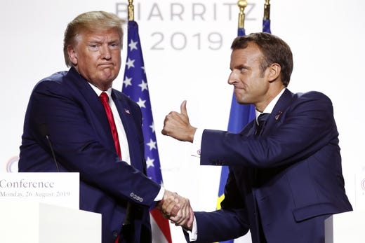 French President Emmanuel Macron and President Donald Trump shake hands and pose as they hold a press conference on the closing day of the G7 summit in Biarritz, France, Aug. 26, 2019.