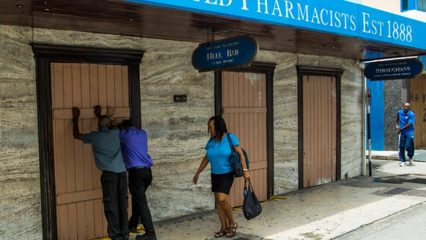 Residents board up a storefront pharmacy as they p