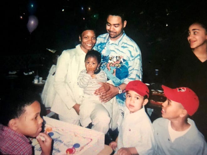 Surrounded by family and friends, Tawan and Antonio Simmons pose for a photo with their son Antjuan during his first birthday party in 2000.