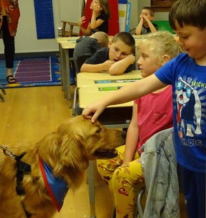 A student in Kim Makeever's first-grade classroom at Bucyrus Elementary School pets Rocky on Tuesday.