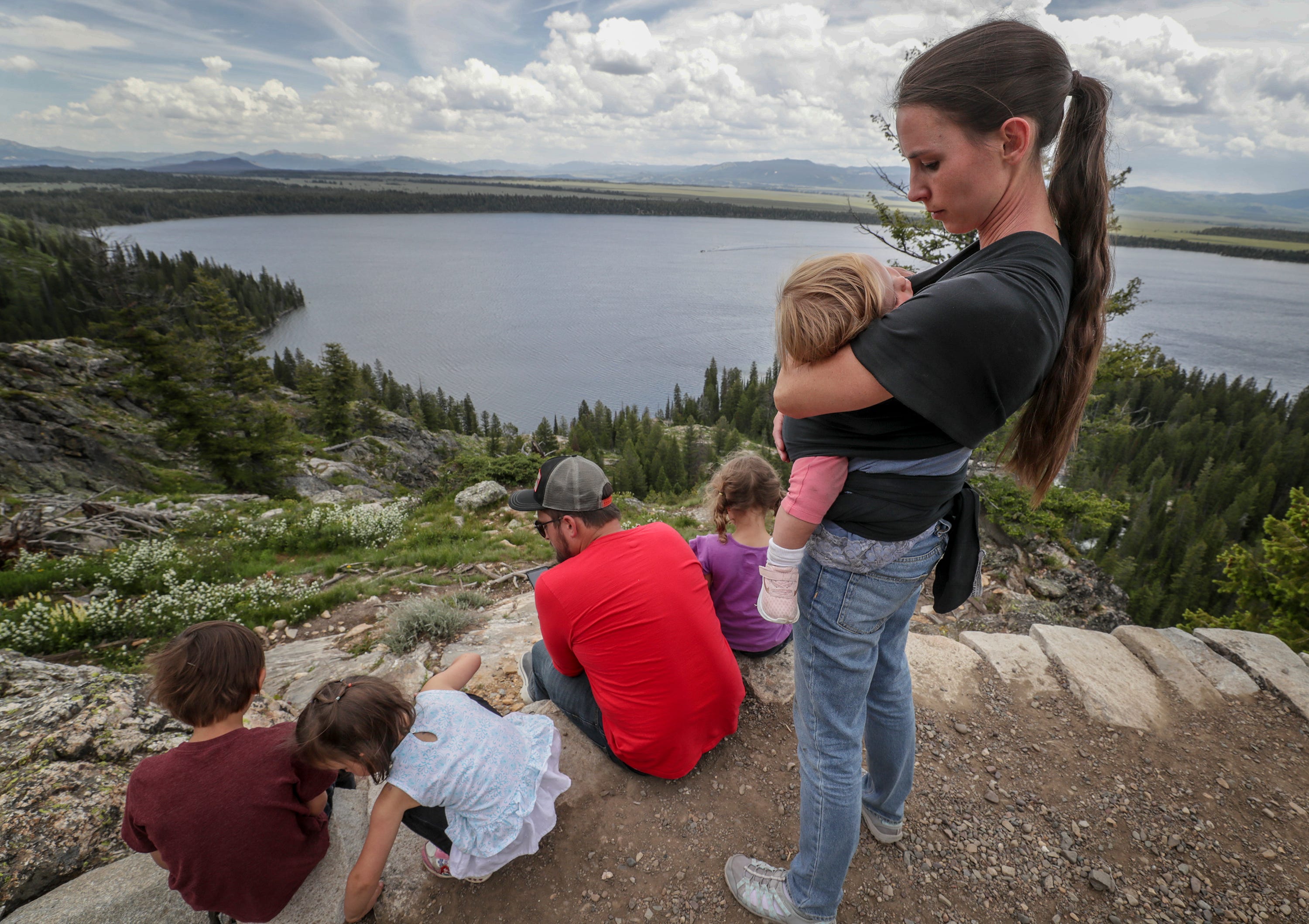 Rachael Denhollander holds her daughter, Elora, as her husband, Jacob, reads the Hobbit to their children at Inspiration Point in Tetons National Park in Wyoming.  Rachael and her family also visited the Tetons when she was a teenager and her father read the Hobbit to them as well.