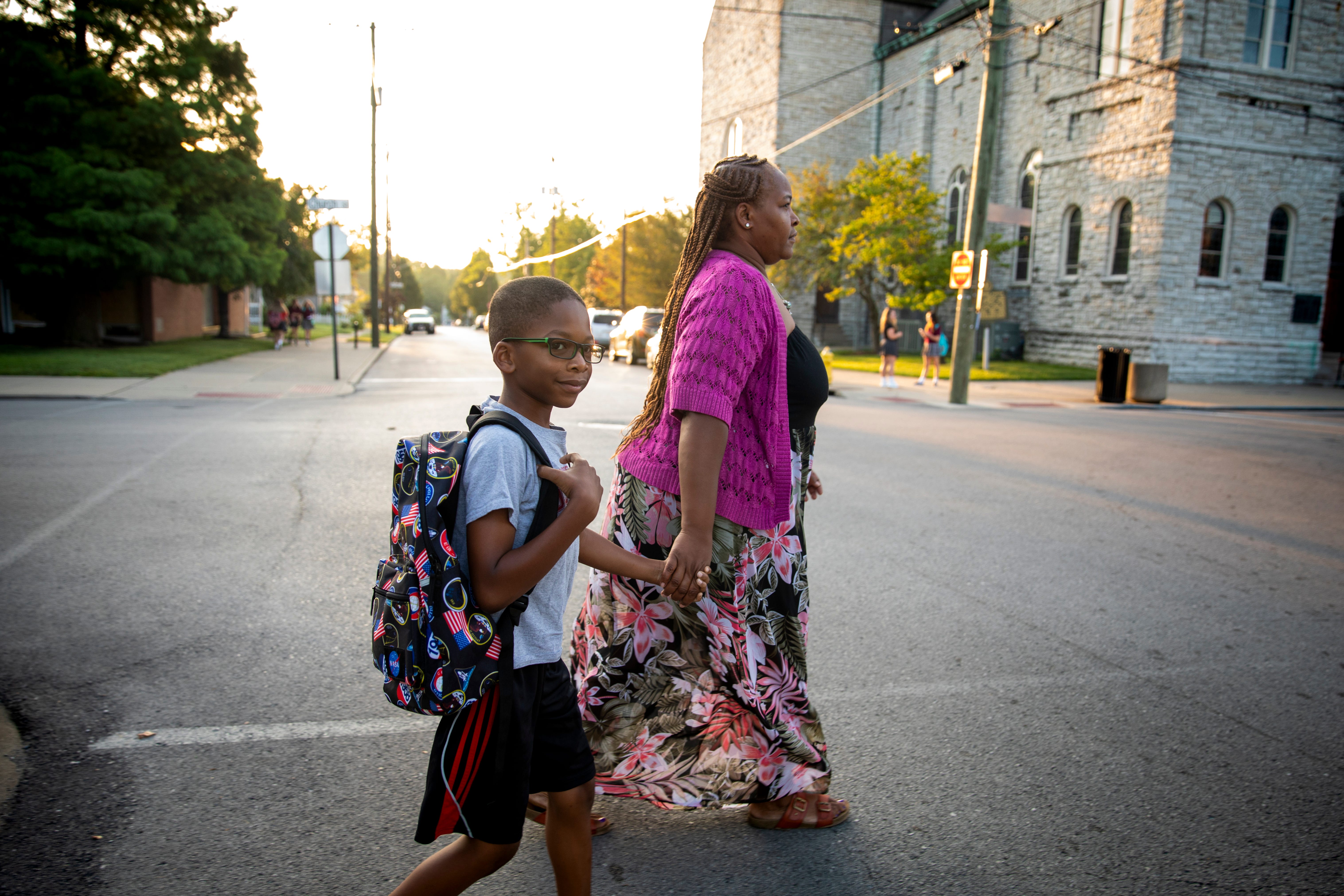 Shannon Glover holds hands with her 8-year-old son, Sidney, as they cross the street to his school in Latonia.