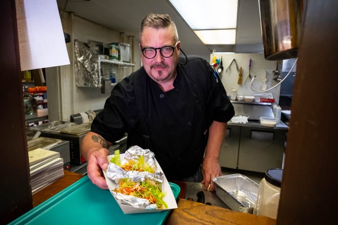 Sean Michael O'Rourke, owner of Chef's Fresco Mexicano, passes two chicken tacos through the service window Friday, Aug. 30, 2019, in his Lexington restaurant.