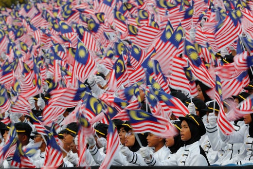 Students wave national flags during 62nd Independence Day celebrations in Putrajaya, Malaysia Saturday, Aug. 31, 2019. The Federation of Malaya gained its independence from Britain on Aug. 31 in 1957. 