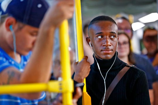 Ty Roberson holds on as he rides a Red Line bus on opening, Sunday, Sept. 1, 2019.