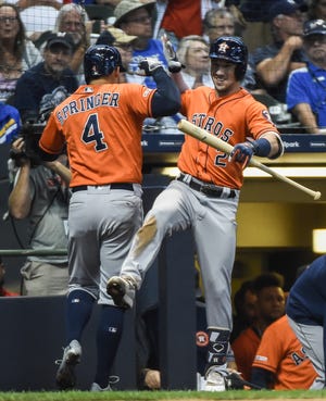 Astros centerfielder George Springer celebrates with third baseman Alex Bregman after hitting a solo home run in the 10th inning Monday at Miller Park.