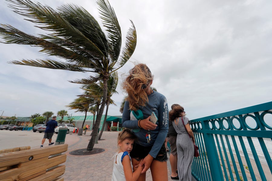 Kristen Davis watches the high surf from a boardwalk overlooking the Atlantic Ocean as she and her daughter Addie, 4, are buffeted by winds from Hurricane Dorian in 2019 in Vero Beach, Fla.