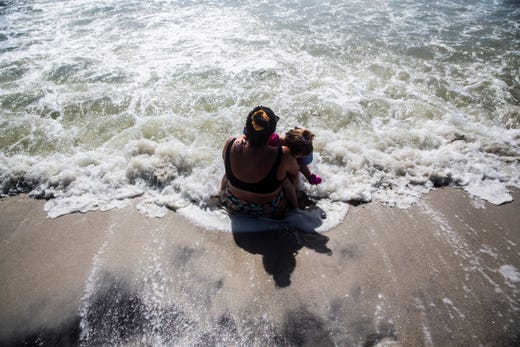 Brittant Cyr holds Brielle Jonathan, 3, in her arms as she sits at the shore of Naples Beach on Tuesday, September 3, 2019. Locals and tourists continue visiting scenic spots in Naples, taking advantage of heavy winds and waves bought on by Hurricane Dorian.