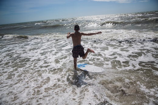 A teenage boy runs into the ocean to catch a wave at the Naples Beach on Sept. 3, 2019. Locals and tourists continue visiting scenic spots in Naples, taking advantage of heavy winds and waves bought on by Hurricane Dorian.