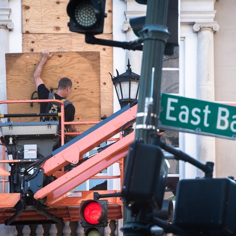 A city worker secures plywood boards over the wind